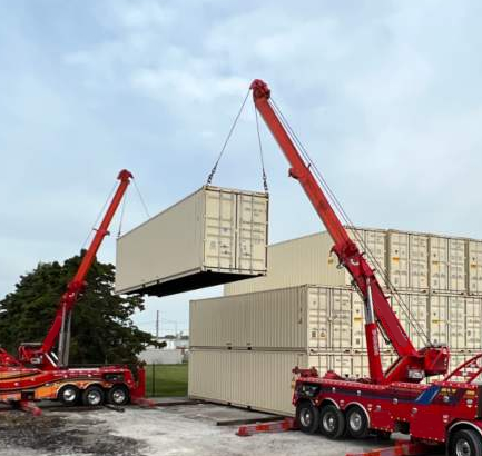 photo shows 2 Big Wheel Wrecker Service wreckers lifting a container